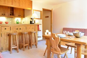 Una cocina de madera con una mesa de comedor y taburetes, una cafetera y una lámpara.
