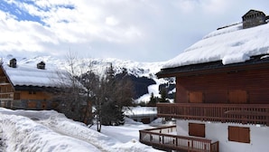 A snow-covered village with wooden buildings, a wooden balcony, and a mountain backdrop. - 150m from ski slopes, 1st floor, balcony, tv, ski locker, 70m², Méribel (Méribel - Les Allues)