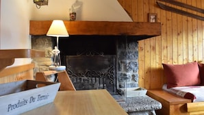 A cozy room with a stone fireplace, wooden furniture, and a sign reading "Produits Du Terroir". - 150m from ski slopes, 1st floor, balcony, tv, ski locker, 70m², Méribel (Méribel - Les Allues)