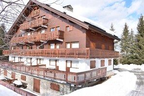 Una cabaña de madera de varios pisos, con balcones, base de piedra y paisajes nevados.