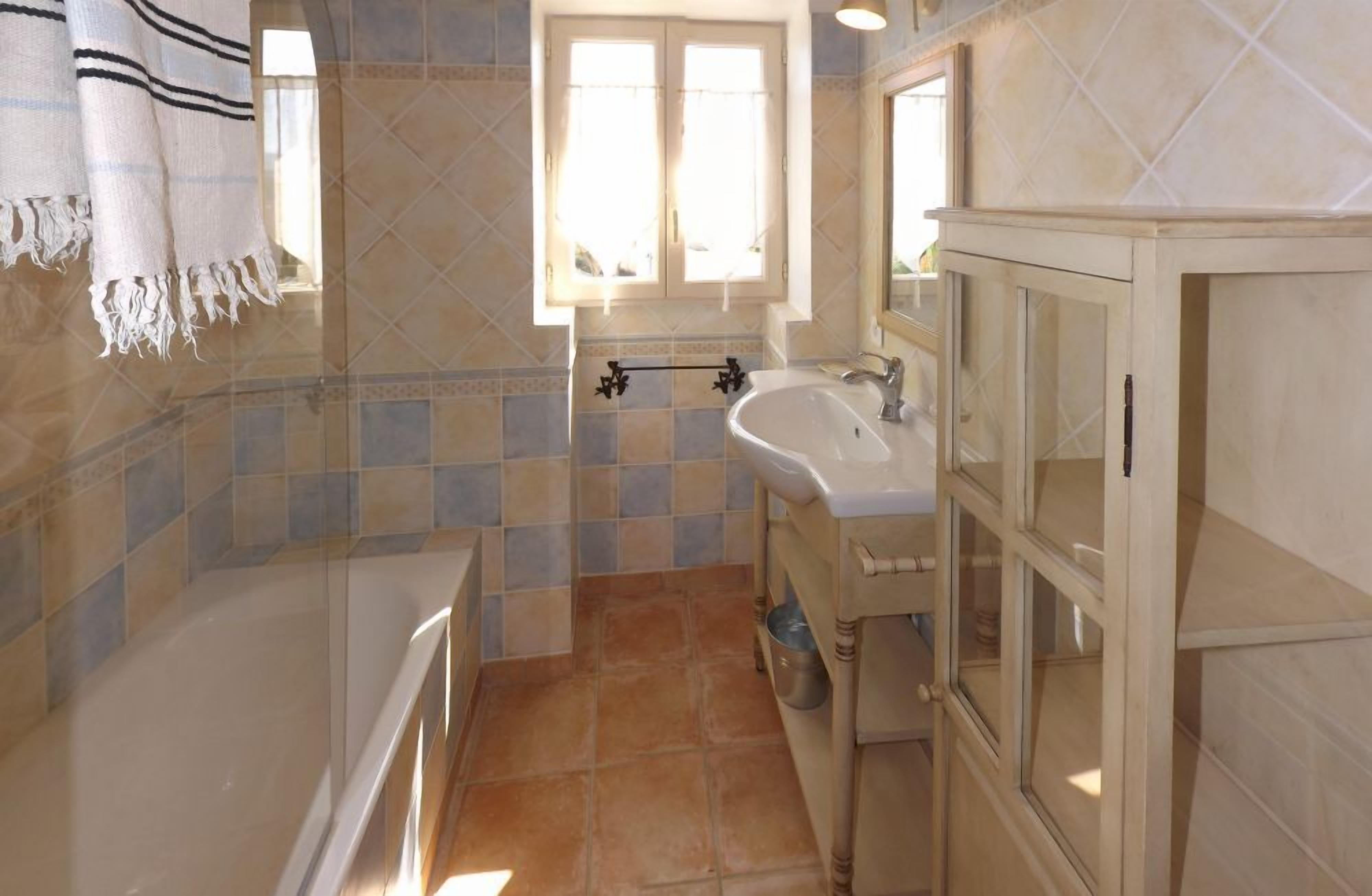 A bathroom with a bathtub, a sink, and a window.