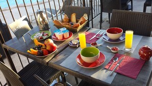 A table set with breakfast items including fruits, bread, and beverages, with a view of the pool in the background. - Mas Dansavan (Oppede)