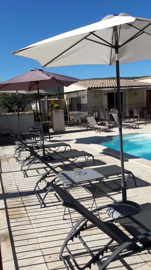 A poolside area with sun loungers, umbrellas, and a clear blue sky. - Mas Dansavan (Oppede)