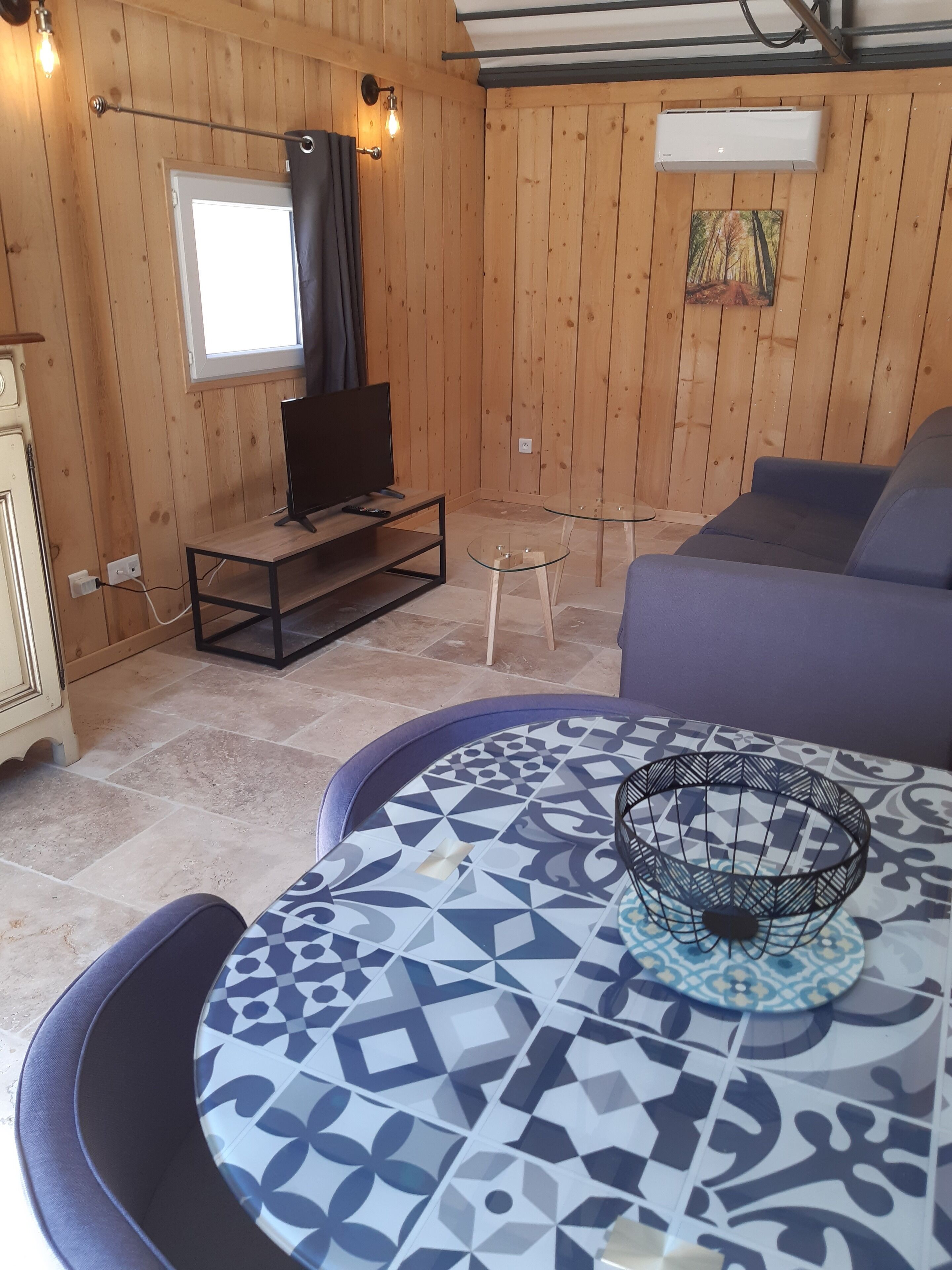 A wooden-paneled room with a TV, sofa, and patterned table.