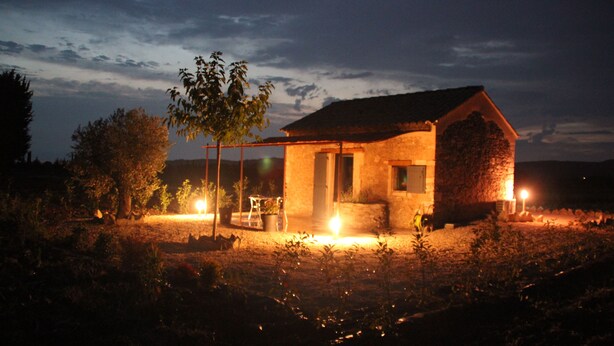 A small stone building with a thatched roof, surrounded by vegetation. - Mas Dansavan (Oppede)