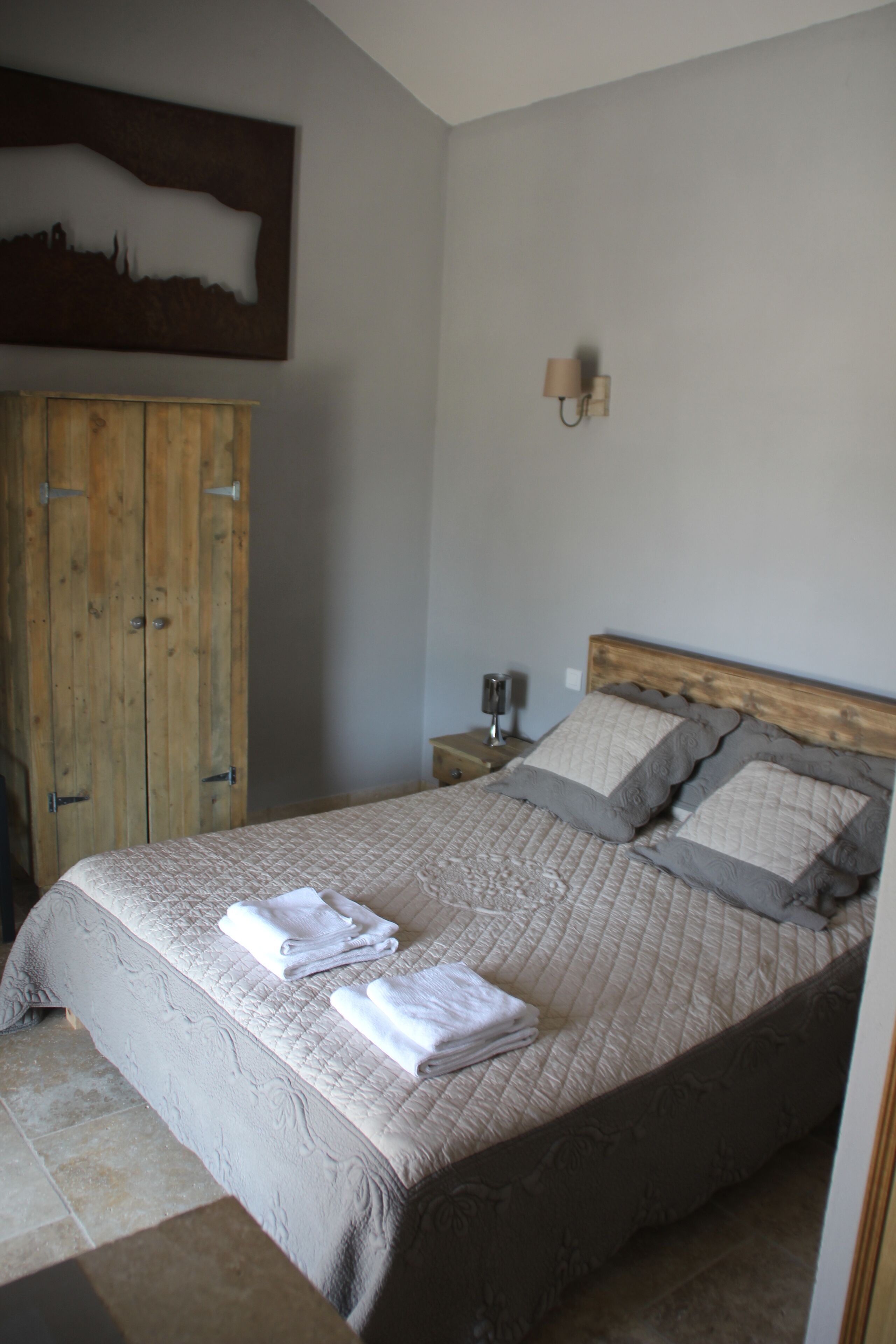 Una camera da letto con un letto grande, un'armadio in legno e una lampada a parete.