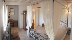 A bedroom with a four-poster bed, a wooden desk, a chair, and a television. - Mas Dansavan (Oppede)