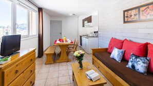 A compact living space with a dining area, kitchenette, and a sofa with red cushions. - 100m from resort center, tv, 36m², Les Angles (Les Angles)