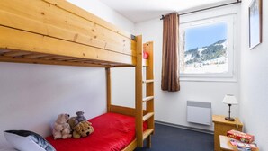 A bunk bed room with a red mattress, a small table with a lamp, and a window with a view of a snowy landscape. - 100m from resort center, tv, 36m², Les Angles (Les Angles)