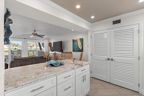 A kitchen with white cabinets, a granite countertop, and a ceiling fan.