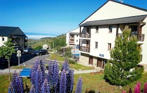 A residential building with balconies, a parking area, and surrounding vegetation. - Wifi, swimming pool, balcony, parking, tv, ski locker, 37m², Font Romeu (Font-Romeu-Odeillo-Via)