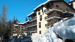 Un hotel a più piani con balconi e una pista da sci sullo sfondo.