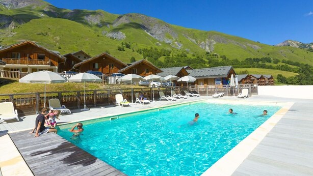 A pool area with wooden deck, lounge chairs, and chalet-style buildings in the background. - Wifi, swimming pool, terrace, parking, tv, ski locker, 42m², Saint Sorlin d'Arves (Saint-Sorlin-d'Arves)