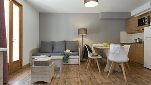 A compact living space with a sofa, dining table, chairs, a lamp, and a kitchenette. - Wifi, swimming pool, terrace, parking, tv, ski locker, 42m², Saint Sorlin d'Arves (Saint-Sorlin-d'Arves)