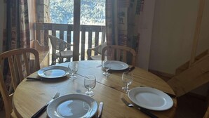 A dining table set for four with chairs, a view of a mountainous landscape through a window, and patterned curtains. - 300m from shops, 2nd floor, balcony, ski locker, 40m², Méribel (Méribel - Les Allues)