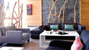 A modern living room with a stone wall, wooden branches, and contemporary furniture. - 300m from resort center, swimming pool, sauna, hammam, terrace, balcony, tv, ski locker, 63-75m² (Les Arcs)