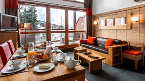 A cozy room with a dining area, a sofa, and a TV. - 300m from resort center, swimming pool, sauna, hammam, terrace, balcony, tv, ski locker, 63-75m² (Les Arcs)