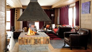 Een gezellige woonkamer met een open haard, lederen meubels en een stenen haardmantel.
