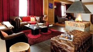 Een gezellige woonkamer met lederen meubels, een open haard en een rood tapijt.
