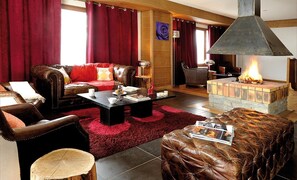 Un salon chaleureux avec des meubles en cuir, une cheminée et une moquette rouge.