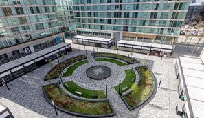 A modern building with a central courtyard featuring a fountain, surrounded by seating areas and greenery. - Grace House • City Centre • Driveway Parking • Pool Table • Sky TV • Fast Wifi • Yoko Property (Milton Keynes)