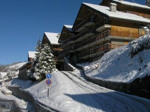 A snow-covered ski resort with multi-story buildings, a ski lift, and a sign indicating no parking. - 250m from resort center, 1st floor, view mountain, tv, ski locker, 42m², Méribel (Méribel - Les Allues)