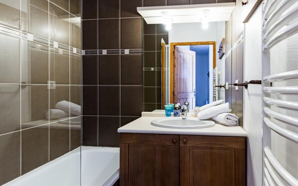 A modern bathroom with a bathtub, a sink, and a mirror.