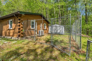 Cozy cabin surrounded by a natural wooded area, featuring a sloped roof and a small window.