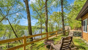 Una terraza de madera con vistas a un lago, rodeada de árboles.