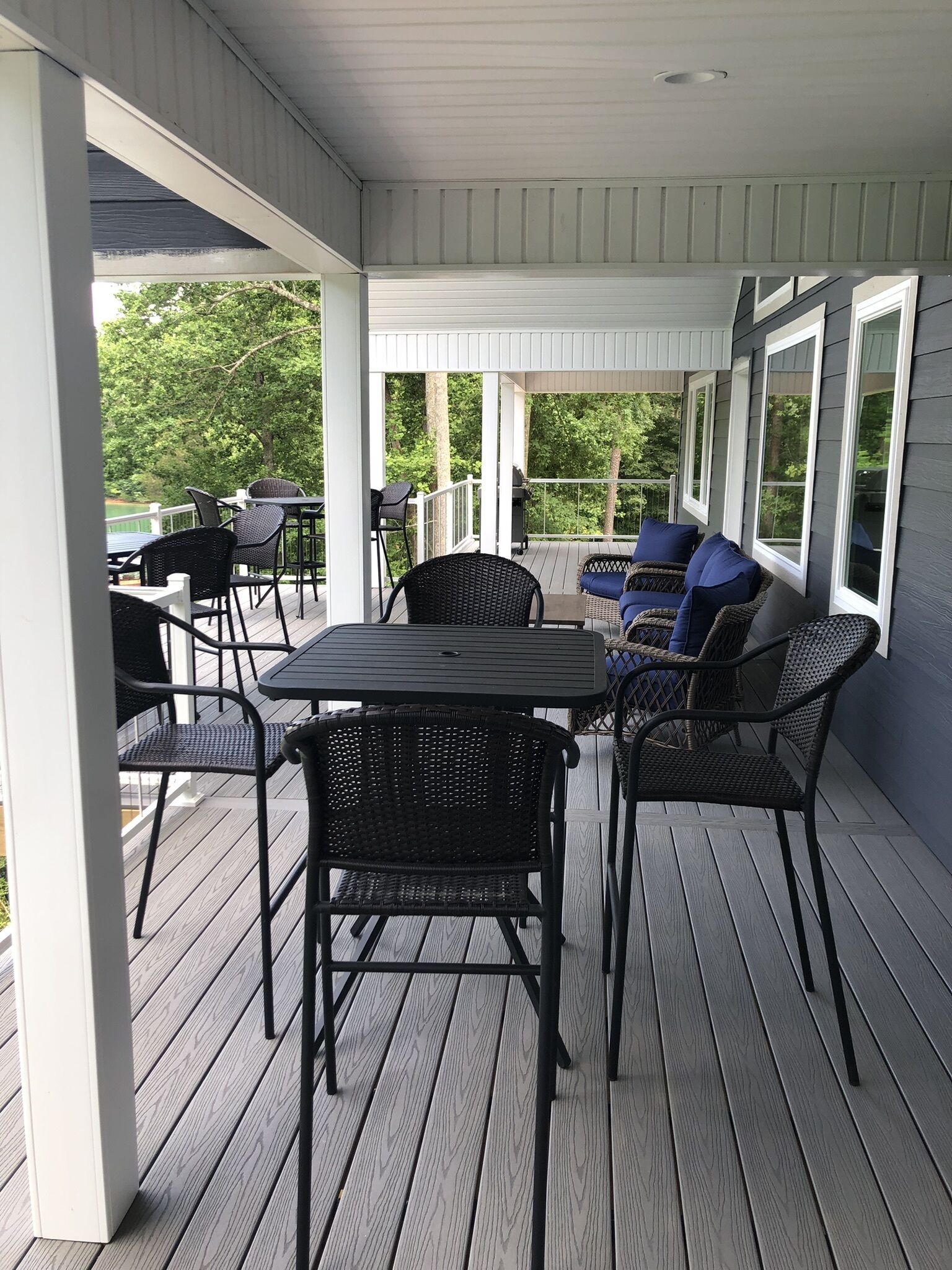A covered outdoor patio with a table and chairs, surrounded by windows.