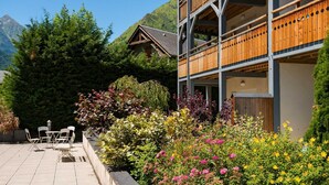 A two-story building with a wooden balcony and a garden with various plants and flowers. - Fitness, swimming pool, sauna, terrace, balcony, tv, ski locker, 48m², Saint Lary Soulan (Saint-Lary-Soulan)