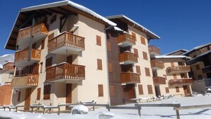 Un immeuble à plusieurs étages doté de balcons, vraisemblablement un hôtel ou un ensemble d’appartements, situé dans un environnement enneigé.