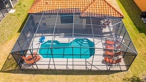 Una piscina rodeada por un cerramiento de cristal y un techo de azulejos.