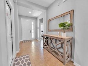 A hallway with a wooden console table, a potted plant, and a mirror on the wall. - Briar Rose 4 Bedroom Villa by RedAwning (Davenport)