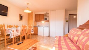 A cozy living room with a sofa and a dining area with wooden chairs and a table. - 1st floor, balcony, tv, ski locker, 40m², Aussois (Aussois)