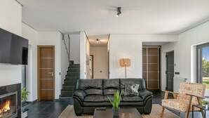 Een moderne woonkamer met een zwarte leren bank, een salontafel en een open haard.