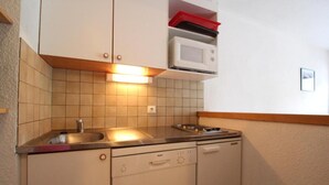Pieni, käytännöllinen keittiö, jossa on pesuallas, liesi ja mikroaaltouuni.
