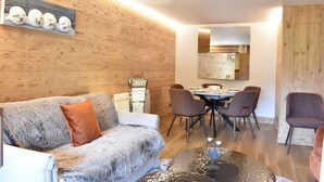 En hyggelig stue med en sofa, et sofabord og et spiseområde med stole og et bord.