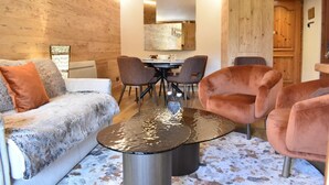 En moderne stue med sofa, to lænestole, sofabord og et spiseområde med stole og bord.