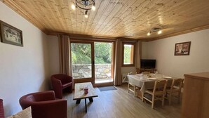 Et værelse med træloft, et spisebord med stole, en sofa og et fjernsyn.
