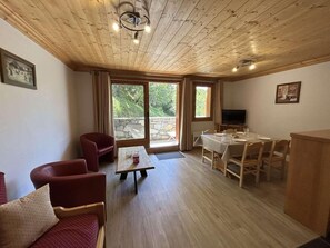 Une pièce avec un plafond en bois, une table à manger avec des chaises, un canapé et un téléviseur.