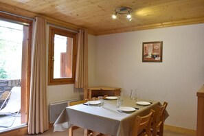 A dining area with a table set for four, wooden chairs, a window with curtains, and a painting on the wall. - 250m from shops, 3rd floor, tv, ski locker, 41m², Méribel (Méribel - Les Allues)