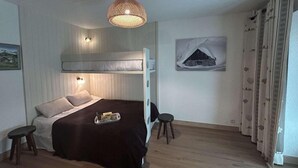 Un dormitorio con literas, una mesita de noche, una lámpara colgante y un cuadro en la pared.