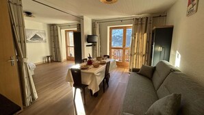Amplia sala de estar con mesa de comedor preparada para cuatro personas, sofá y televisor.