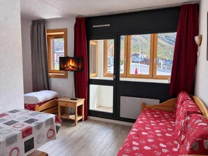 Una habitación con cama, una mesa, una silla, chimenea y vistas al exterior.