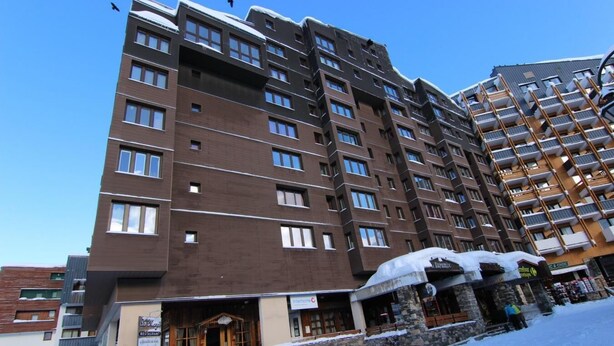 A multi-story hotel with a modern architectural design, featuring a stone facade and a wooden entrance. - 200m from resort center, 4th floor, balcony, 28m², Val Thorens (Val Thorens)