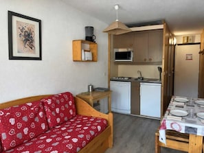 Un espacio habitable funcional con sofá, kitchenette y comedor.