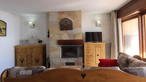 Una sala de estar acogedora con chimenea de piedra, muebles de madera y un televisor.