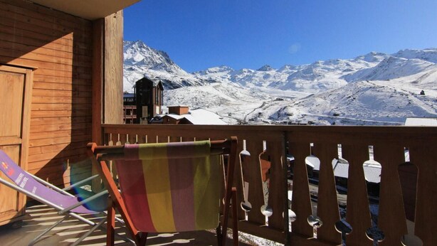 Un balcón de madera con vista a montañas nevadas.