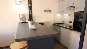 Una cocina compacta con una isla central, cafetera y lavavajillas.